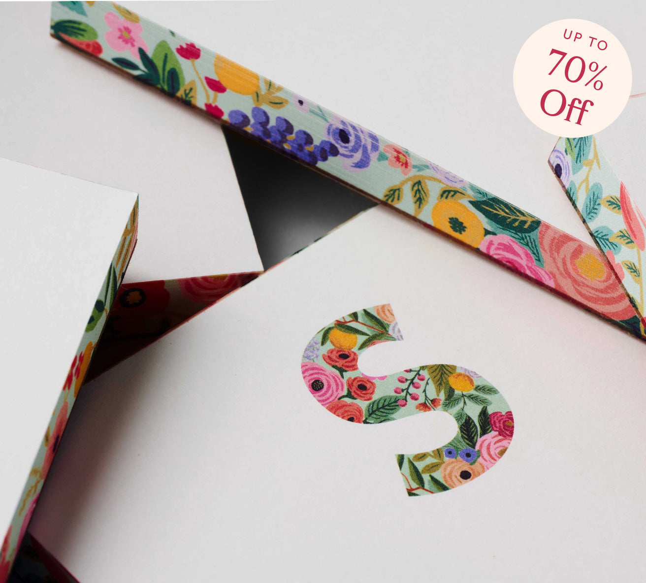 Floral-patterned ribbon and letter 'S' on a white background with a discount label.